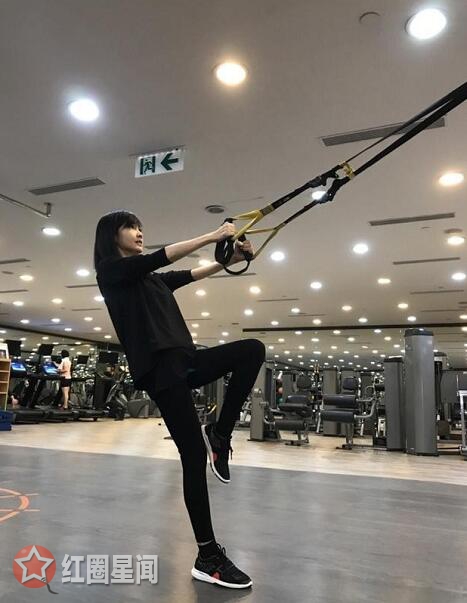 在照片当中的周慧敏身穿黑色运动套装在进行着健身运动
